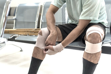 Close up man patient wrapped elastic bandage on his injured knee