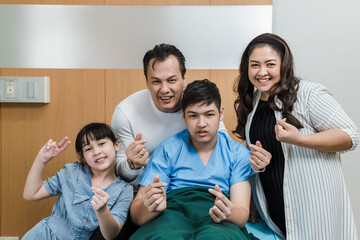 Obraz premium Happy Asian family with father,mother, daughter and patient son making miniheart symbol hands in hospital room, Hospital business