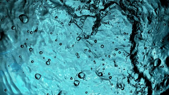 Super slow motion of water surface with bubbles on light blue background. Filmed on high speed cinema camera, 1000 fps.