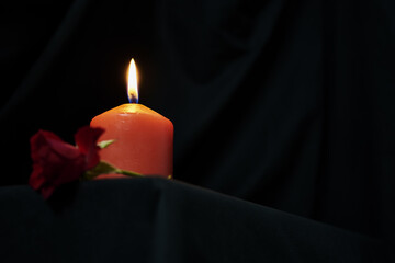 a red burning candle and a red rose on a black background copy space gothic style