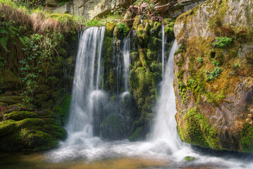 Fototapeta na wymiar Small waterfall on a mossy wall in a limestone gorge