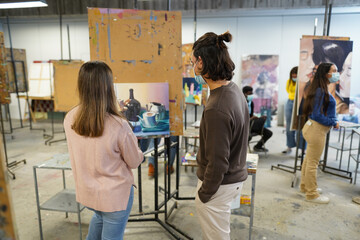 Young students painting inside art room class at college - Focus on guy head