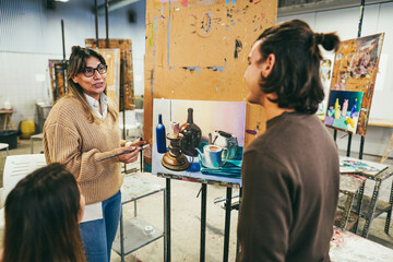 Mature teacher working with art students during painting class at school - Focus on teacher face