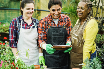 Multiracial women working inside greenhouse garden - Main focus on center farmer face