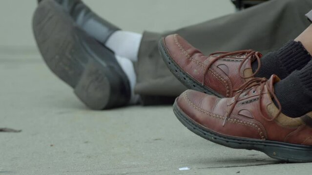 Close up of shoes. Homeless people sitting on New York street. Slow-mo