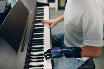Young disabled man play on piano electronic synthesizer with artificial prosthetic hand in music shop