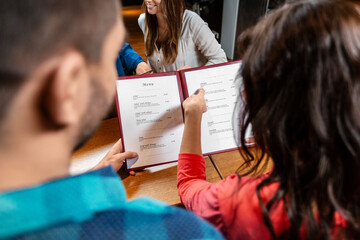 leisure and people concept - close up of couple with menu at restaurant