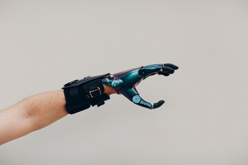 Disabled man with artificial prosthetic hand close up male hand against gray background