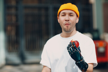 Young disabled man hold apple with artificial prosthetic hand in casual clothes