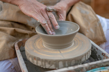 Fototapeta na wymiar artigiano lavora un vaso l'argilla sul tornio per la ceramica