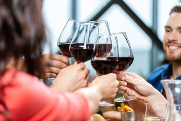 leisure, people and celebration concept - close up of happy friends drinking red wine and toasting at restaurant or pub