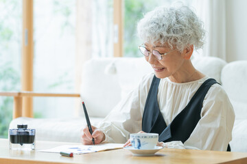 リビングで手紙を書くシニア女性