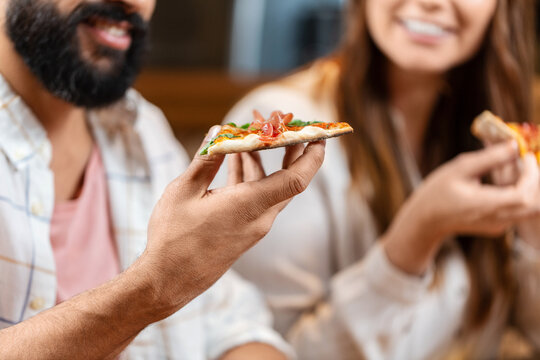 leisure, food and drinks, people and holidays concept - close up of happy smiling friends eating pizza at restaurant or pub