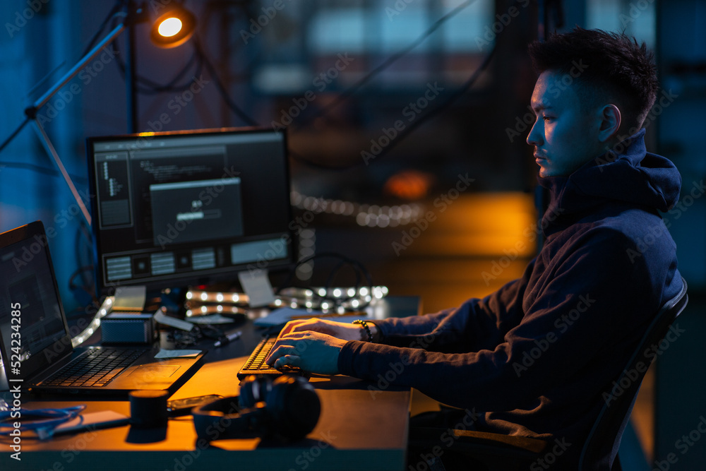 Poster cybercrime, hacking and technology concept - male hacker in dark room writing code or using computer