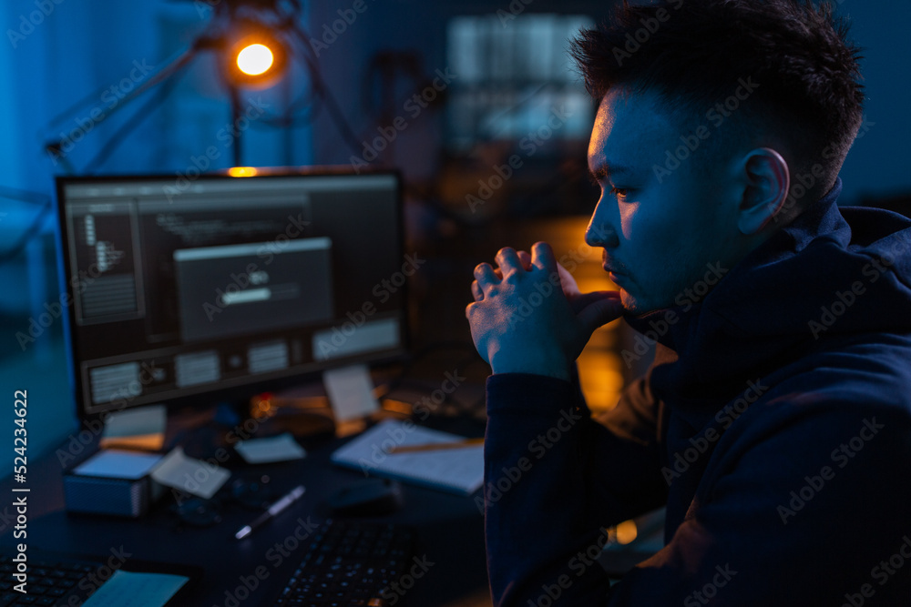 Poster cybercrime, hacking and technology concept - close up of male hacker in dark room using computer vir