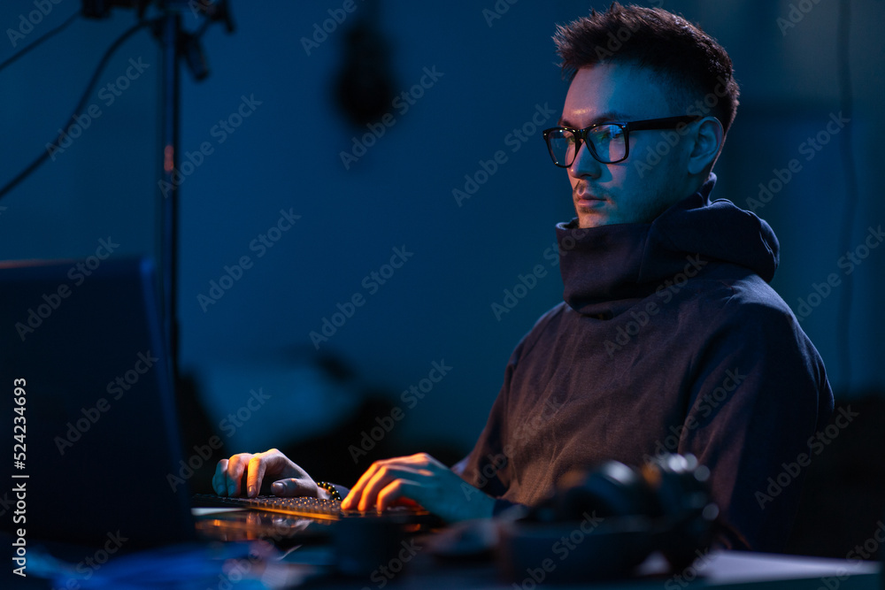 Poster cybercrime, hacking and technology concept - male hacker in dark room writing code or using computer