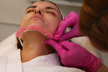 Close up face of thread lifting procedure. Professional cosmetologist in pink medical gloves...