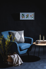 interior and home decor concept - close up of blue chair, coffee table and blanket in basket in dark room