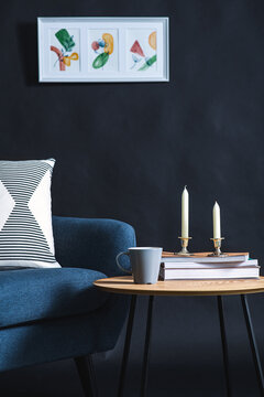 interior and home decor concept - close up of blue chair, coffee table and picture on black wall in dark room