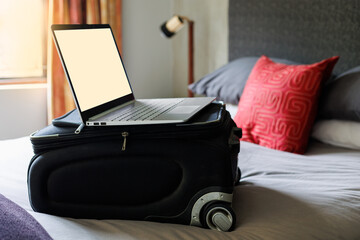 laptop on suitcase on a grey bed