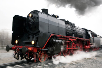 Eine Dampflokomotive spuckt Rauch und Dampf bei voller Fahrt mit wischeffekt durch...