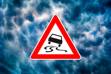 Ein dreieckiges Piktogramm mit Gefahrenhinweis vor dramatsichem Himmel