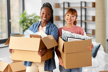 moving, people and real estate concept - happy smiling women with boxes at new home