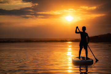 Kind auf einem Stand Up Paddle schwimmt den Sonnenuntergang entgegen