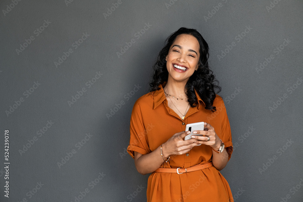 Wall mural laughing happy smiling woman messaging on mobile phone on gray wall