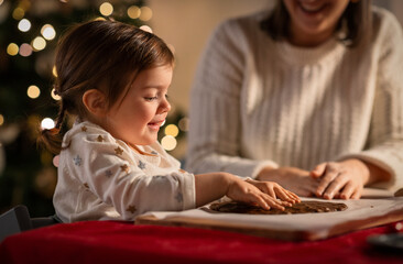 family, cooking and winter holidays concept - happy mother and baby daughter having fun with dough...