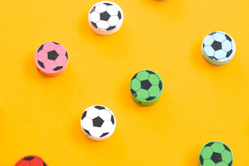 Wooden figures in the form of soccer balls on a yellow background