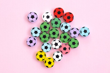 Wooden figures in the form of soccer balls on a pink background. Football time.