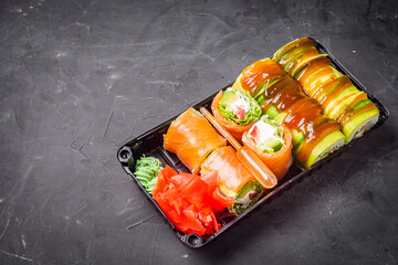 delicious sushi rolls in a delivery box on a black background