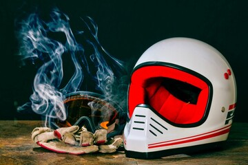 Closeup of a helmet, goggles, and gloves on a table with smoke.
