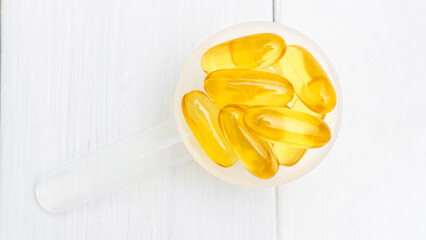 Omega-3 yellow capsules in a plastic scoop, nutritional supplements, close-up, top view