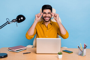 Portrait of cheerful clever agent man sit chair arms touch glasses use netbook workplace isolated...
