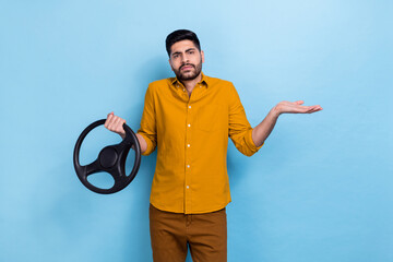 Photo of sad brunet millennial guy hold wheel wear yellow shirt isolated on blue color background
