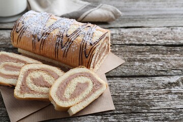Tasty cake roll with cream on wooden table, space for text
