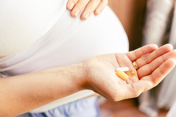 Obraz na płótnie Canvas Pregnant medication vitamin pill. Happy young pregnant woman holding supplement vitamin pill. Diet nutrition. Healthy eating, lifestyle.