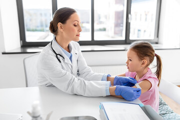 medicine, healthcare and vaccination concept - female doctor or pediatrician attaching medical...