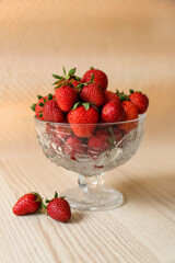 Glass dessert bowl with ripe strawberries on white wooden table
