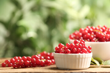 Ripe red currants on wooden table against blurred background. Space for text