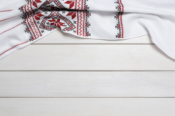 Beautiful rushnyk on white wooden table, top view with space for text. Ukrainian national embroidery