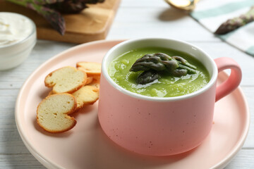 Delicious asparagus soup served on table, closeup