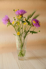 Bouquet of beautiful wildflowers in glass vase on wooden table