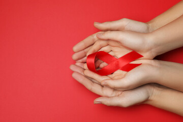 Woman and girl holding red ribbon on bright background, top view with space for text. AIDS disease awareness