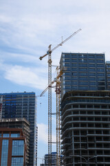 Construction site with tower cranes near unfinished building, low angle view