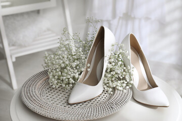 Beautiful wedding shoes, engagement ring and flowers on table indoors, closeup