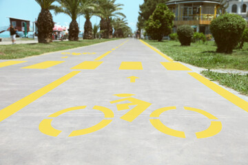 Obraz premium Bike lane with painted yellow bicycle sign and arrow near pedestrian crossing, closeup