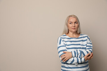 Emotional mature woman on beige background. Space for text